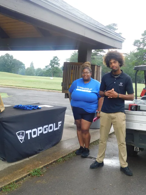 Supporters beside the Topgolf display at COMEC’s 2026 golf tournament