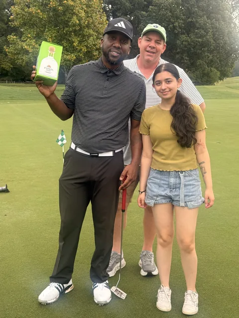 Three supporters posing together on the course at COMEC’s 2026 golf tournament