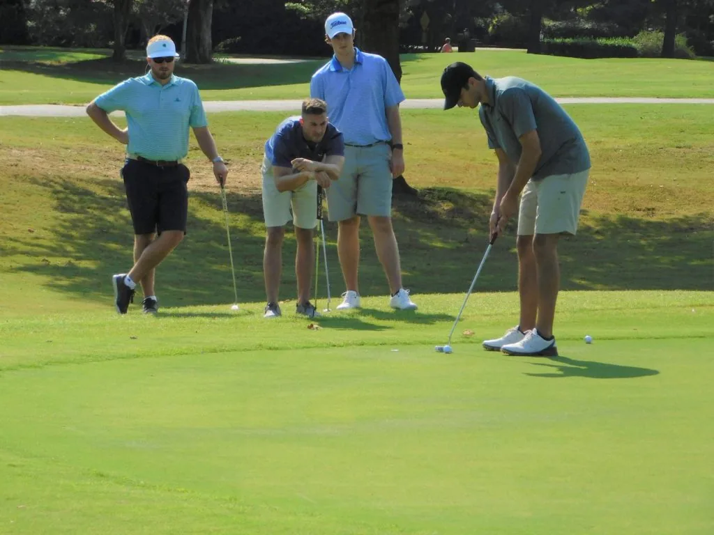 Golfers gathered around a putting green at a COMEC Golf Tournament
